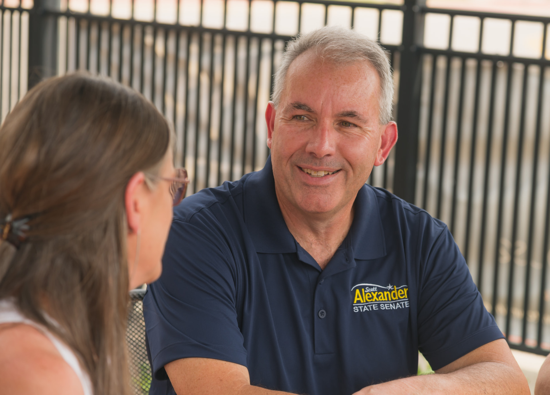 Scott Alexander listening to a resident during a conversation outdoors.