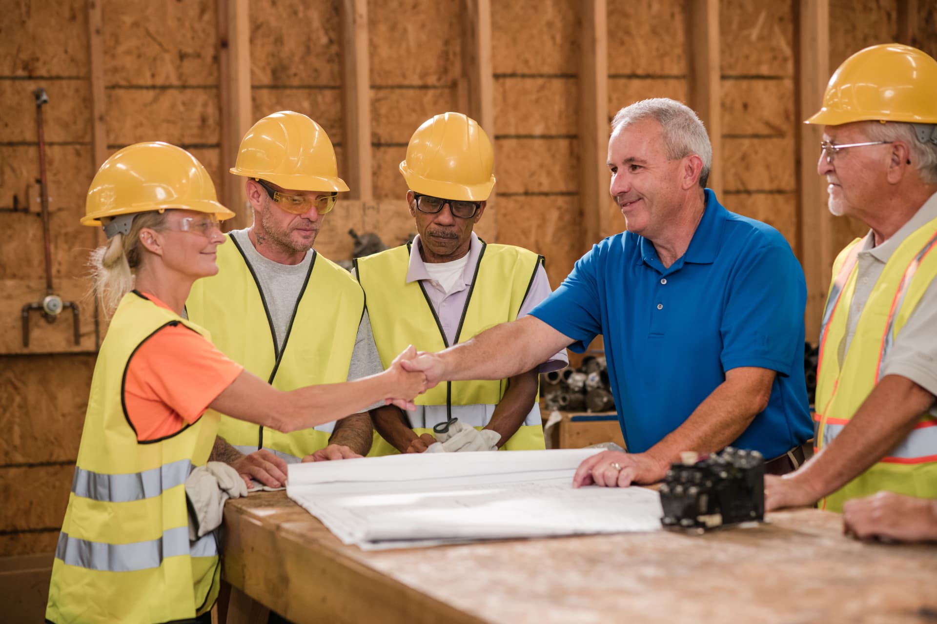 Scott Alexander shaking hands with local workers reviewing plans